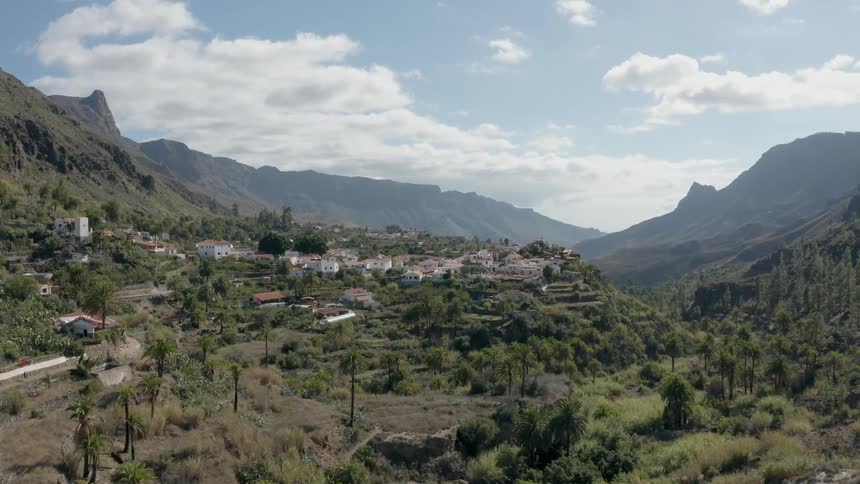 Buildings cluster in a village in a mountain range on a sunny day