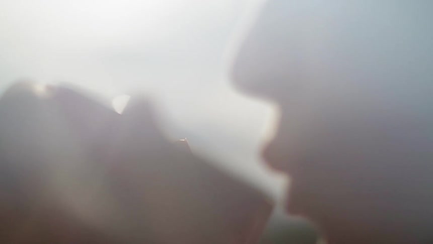 A woman sips from a steamy mug outside
