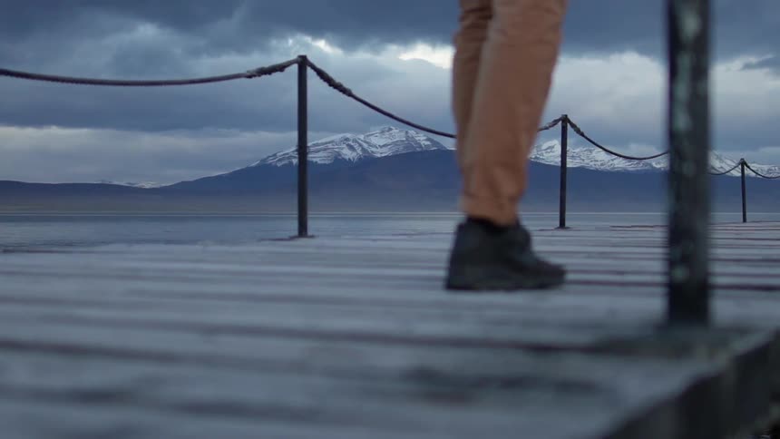 A man walks on a dock with his hands in his pockets