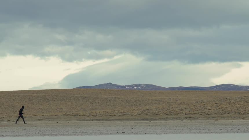 Person walks out in the country near hills on a cloudy day