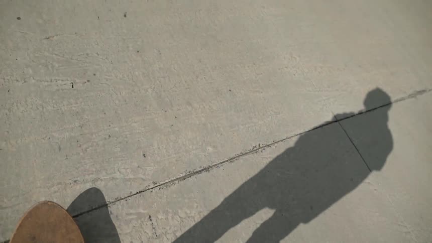 A skateboarder rides on a sidewalk