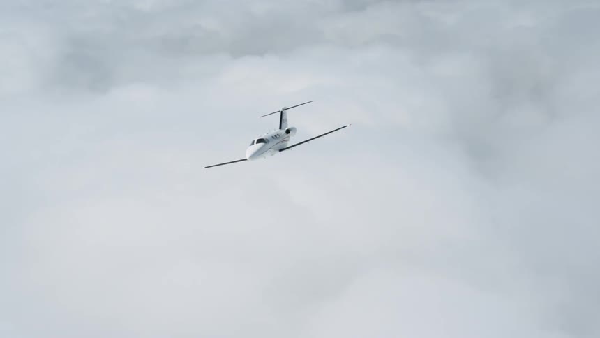 White jet flies above the clouds