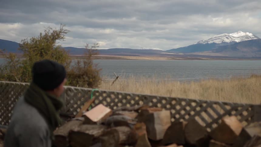 Man in a toque looks towards the snow covered mountains