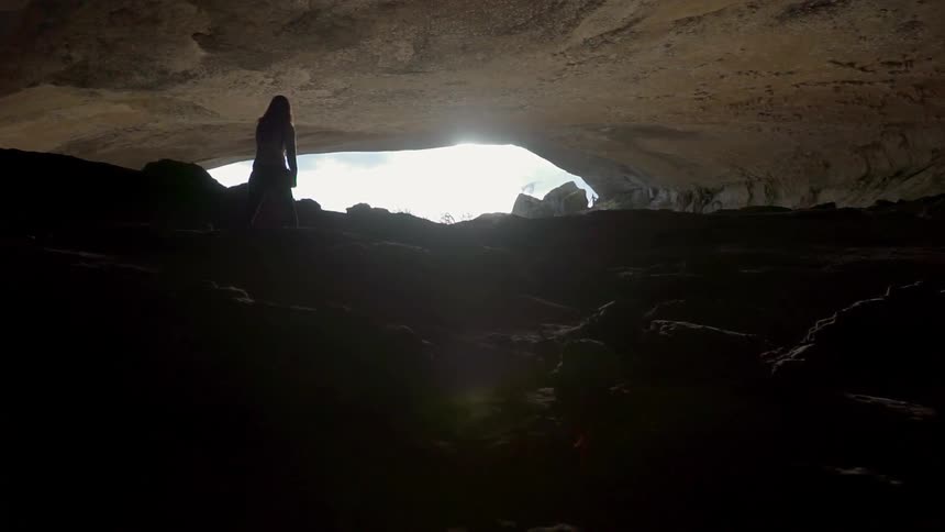 Person walks in a cave out towards the sun