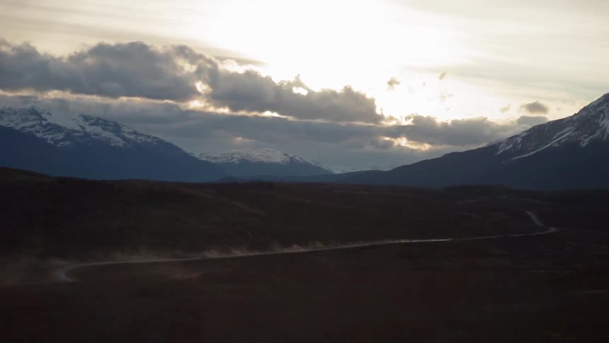 Clouds roll over snowy mountains on a sunny day
