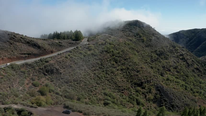 The vehicle drives up the trail on the fog covered mountain