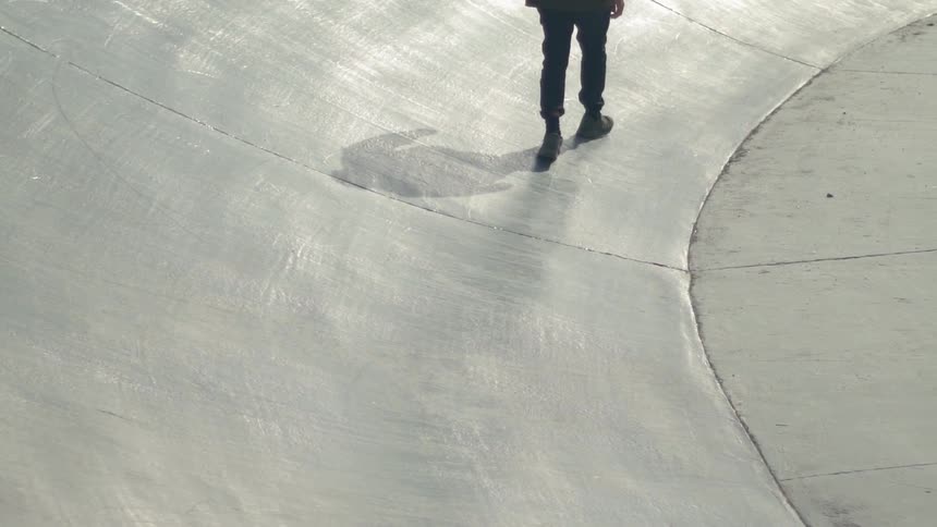 Person walks on concrete surface illuminated by the sun