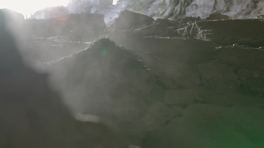 Steam is rising up from rocks in a natural setting during the day