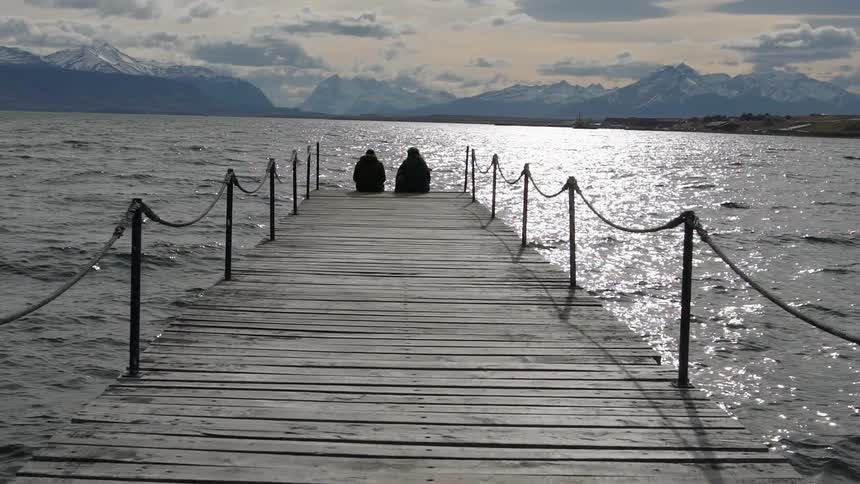 Two people sit on the end of the pier together
