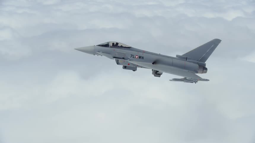 A fighter jet is flying above the clouds in daylight