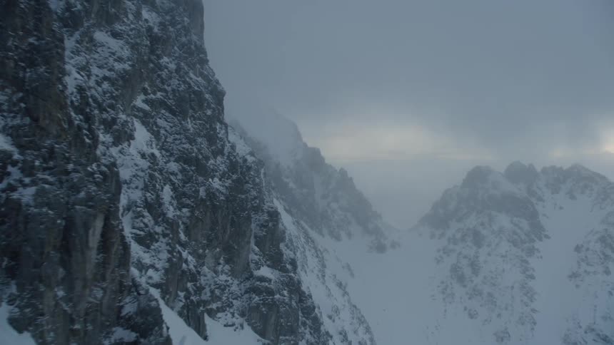 The tall snow covered mountain is covered with fog ahead