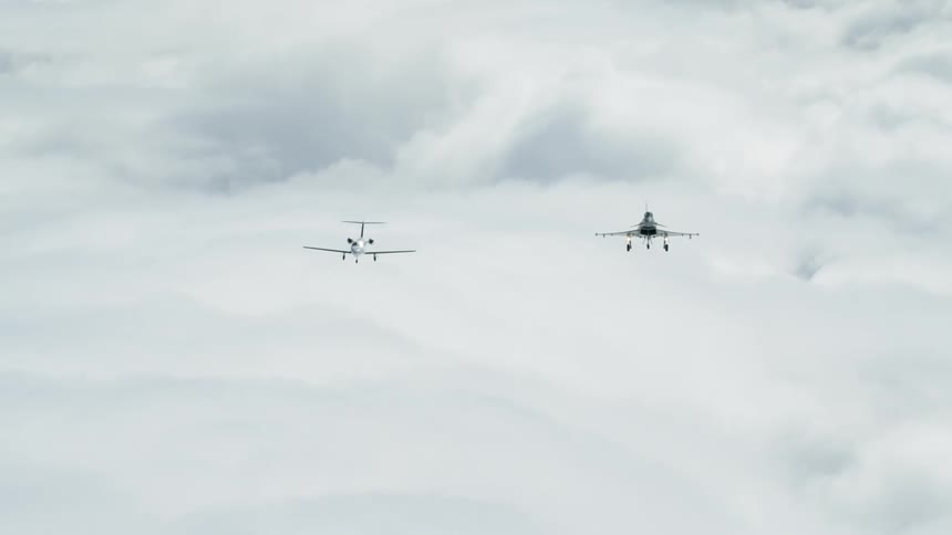 Two airplanes soar in the sky on a cloudy day