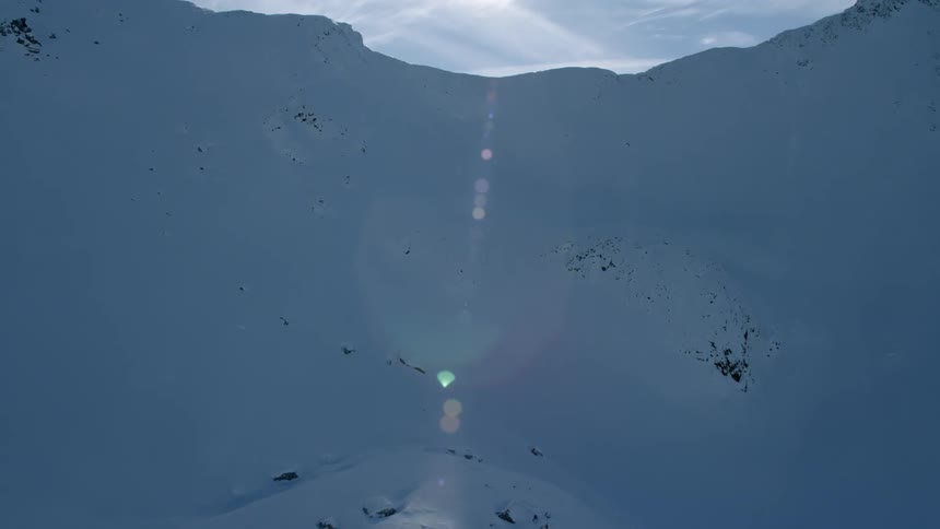 Snow is covering the slopes of a mountain range during the day