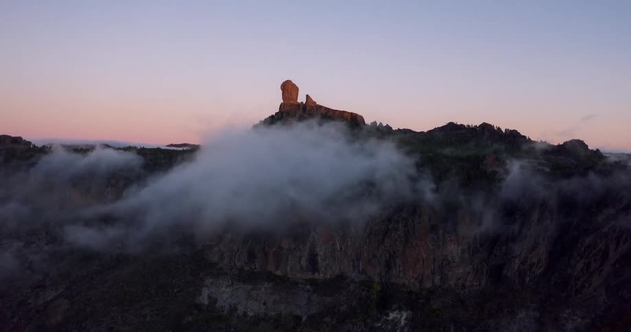 Clouds float around a cliff at sunrise