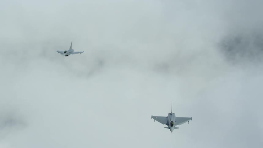 Two airplanes soar in the sky on a cloudy day