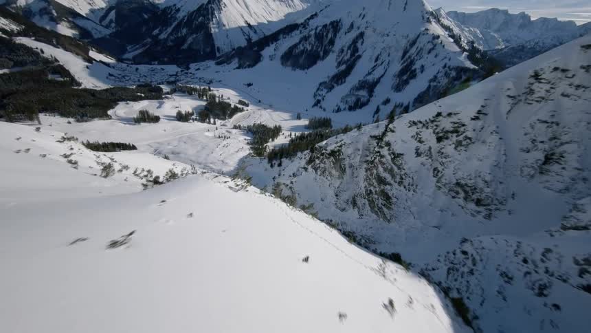 Snow is covering the slopes of a mountain range during the day