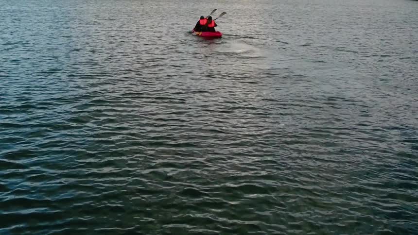 Two people paddle a dinghy through the water