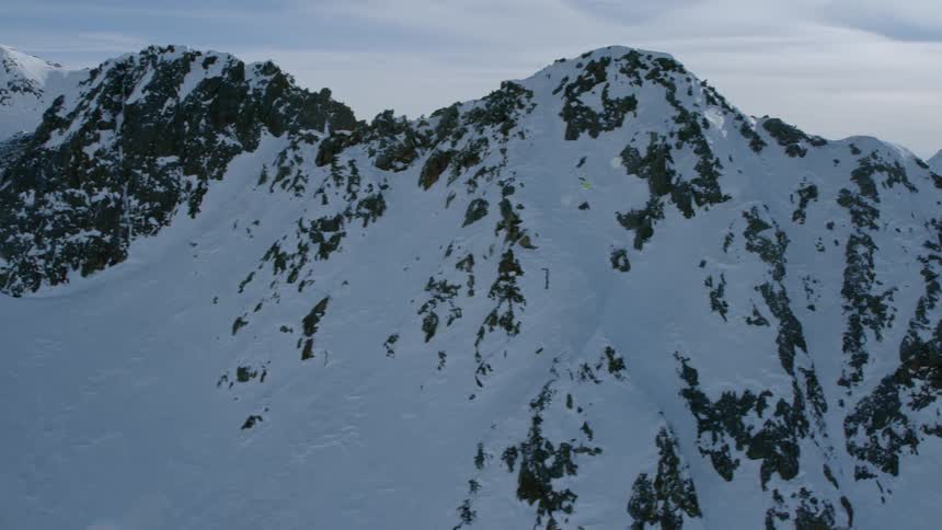 Snow is covering the slopes of a mountain range during the day