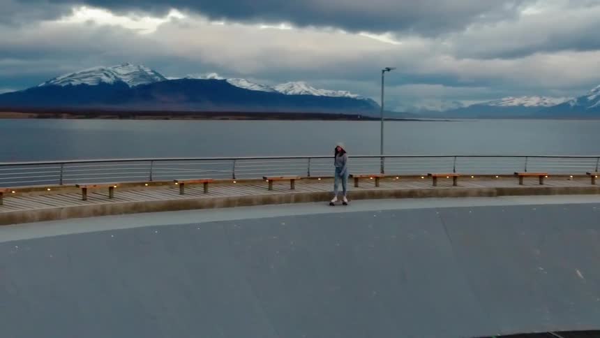 Person rides a skateboard high on a concrete ledge next to a body of water