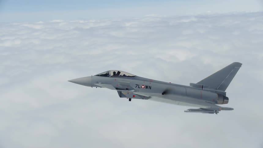 A fighter jet flies above clouds