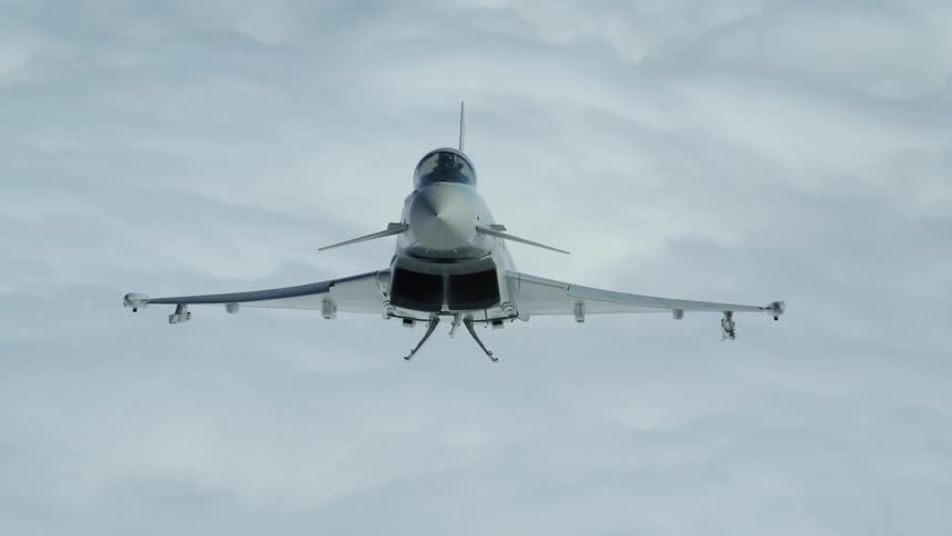 A jet flies above clouds in the sky