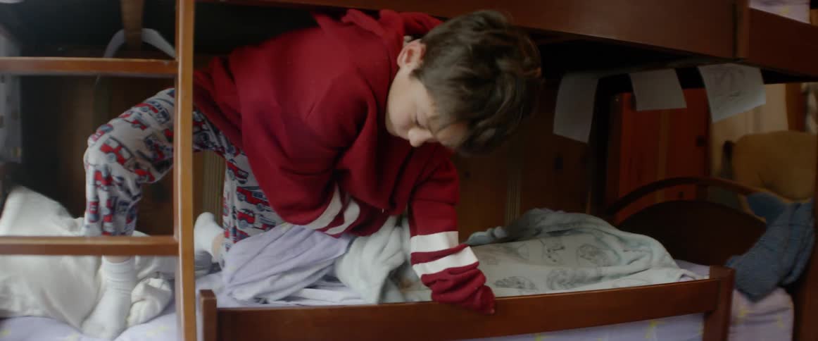 A boy climbs out of a bunk bed