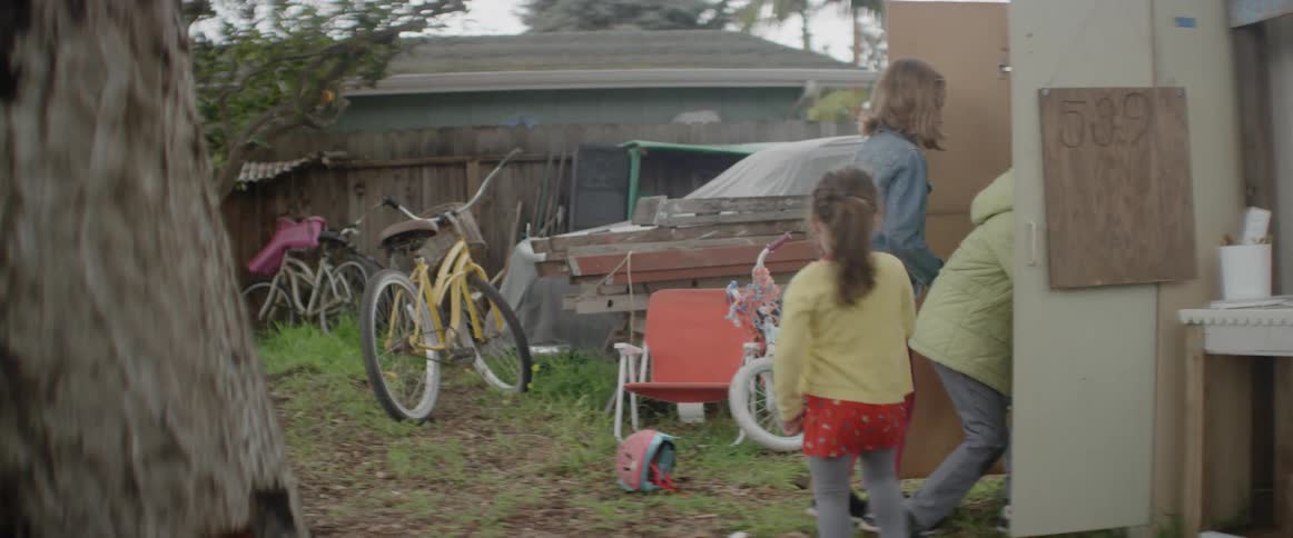 Three children are walking to a cabinet in a backyard and opening in daylight