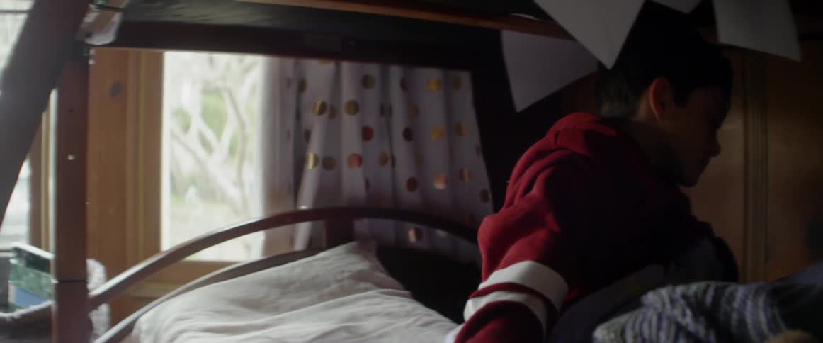 A boy is getting up from bed in the morning