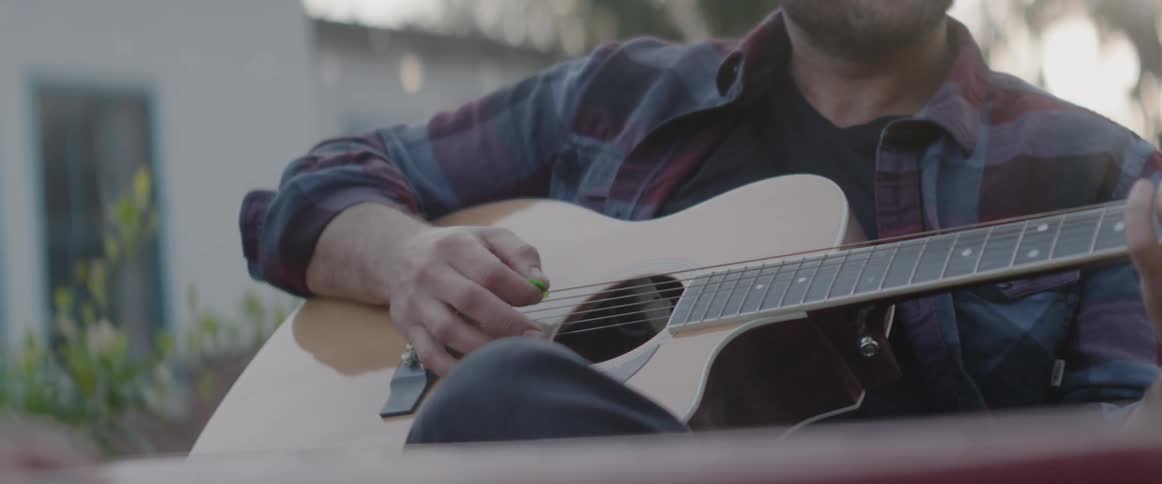 Man plays the guitar outside on a sunny day