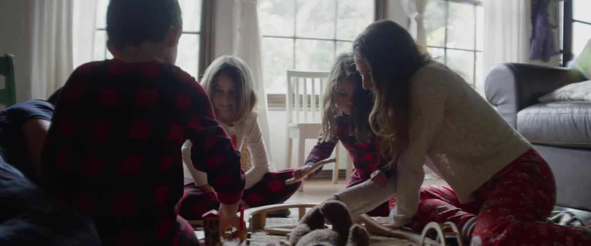 A family plays with toys on a living room floor
