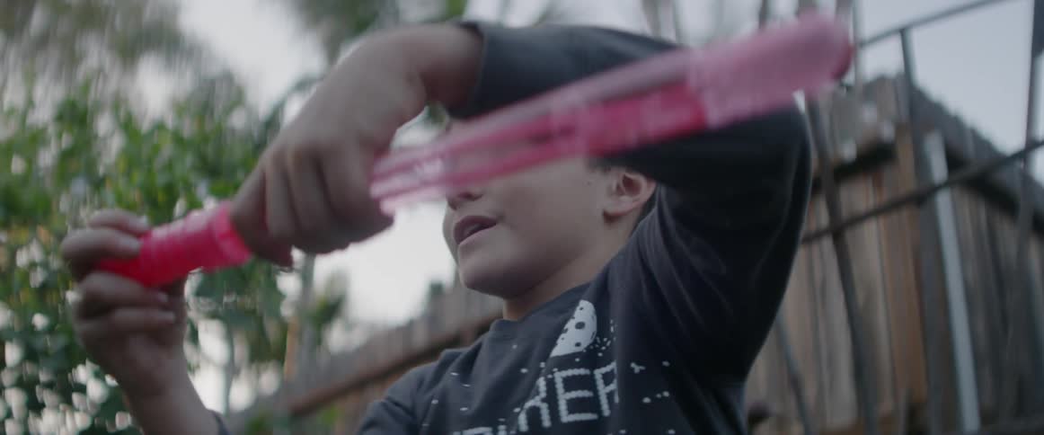 A boy is playing outside in a backyard in daylight