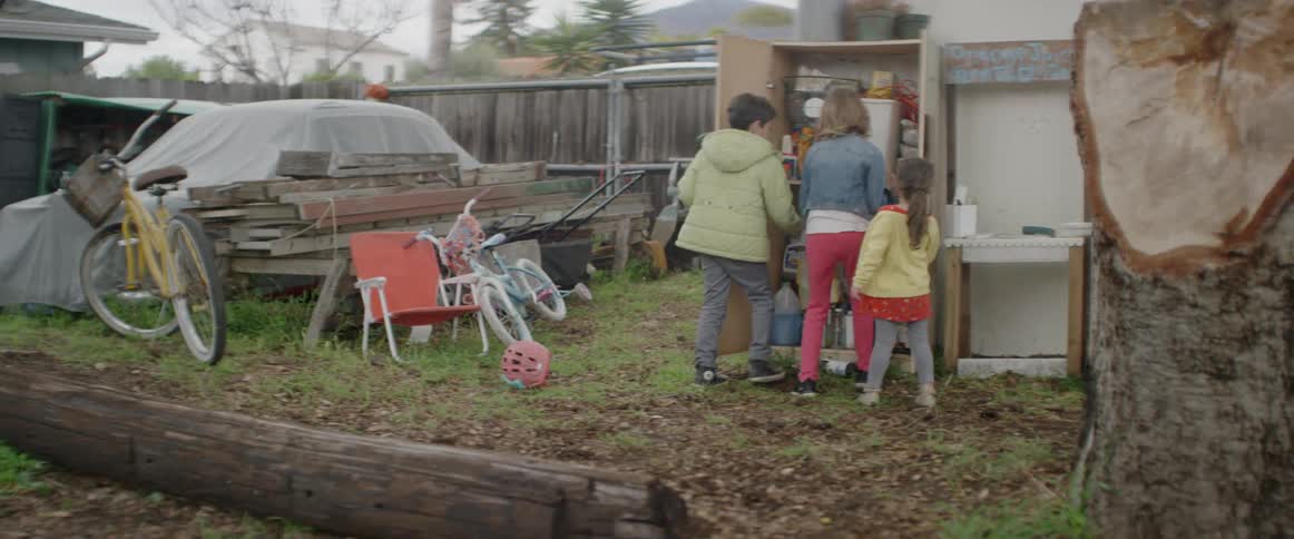 Children are retrieving items from a cabinet in a backyard during daylight