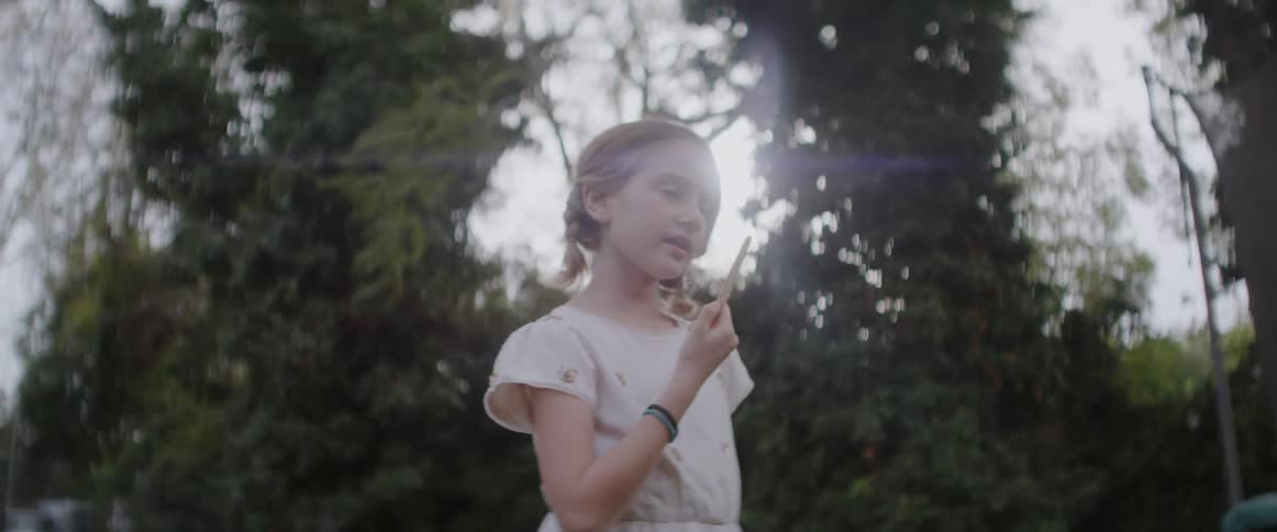 Young girl licking the endings from a popsicle stick outdoors