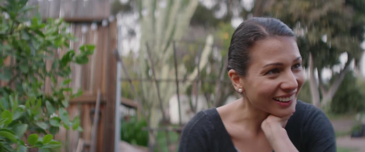 Smiling woman stands outside in a yard