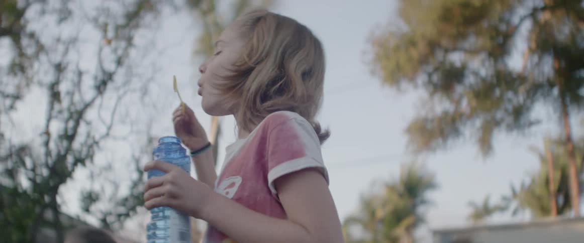 A girl blows bubbles outside