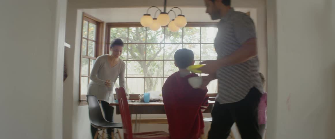 The child walks into the dining room as the family leaves