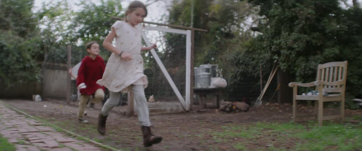 Children are running through a backyard in daylight