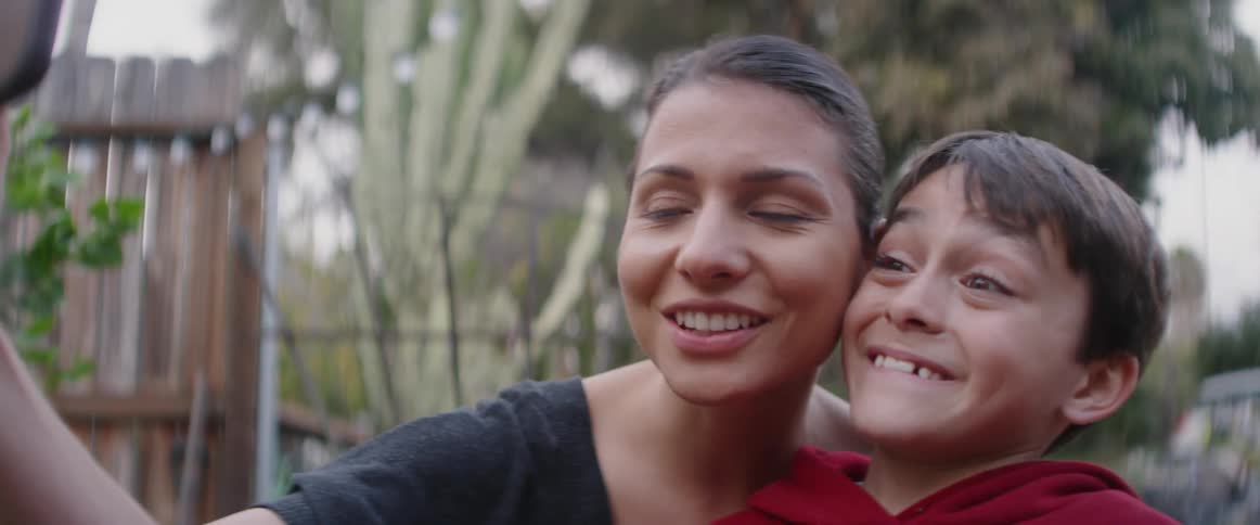 A woman and young boy smile and take a selfie