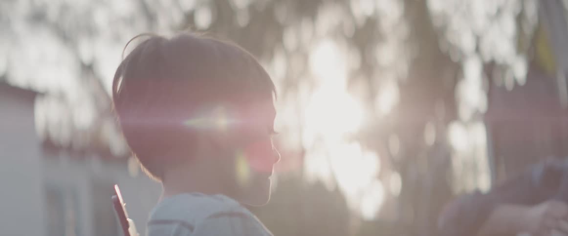 Child sits in a chair outside on a sunny day