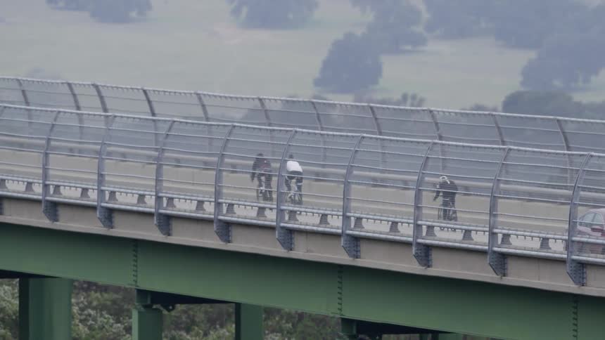 Bikers are crossing a bridge