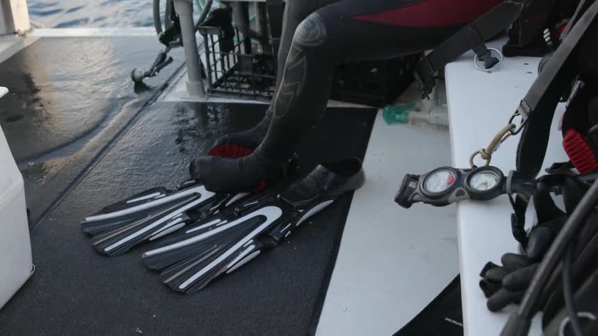 A person takes off their diving flippers