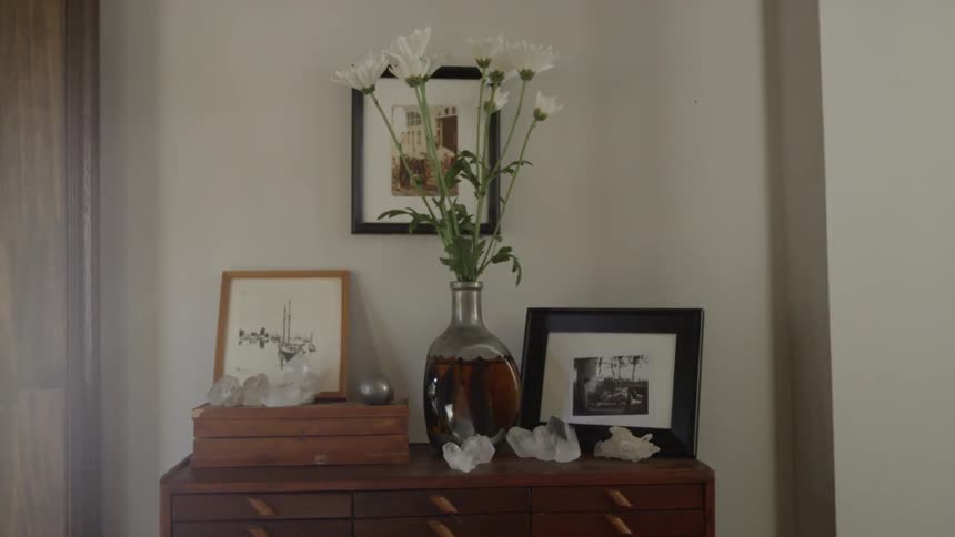 View of the top of a dresser decorated with pictures and a flower vase