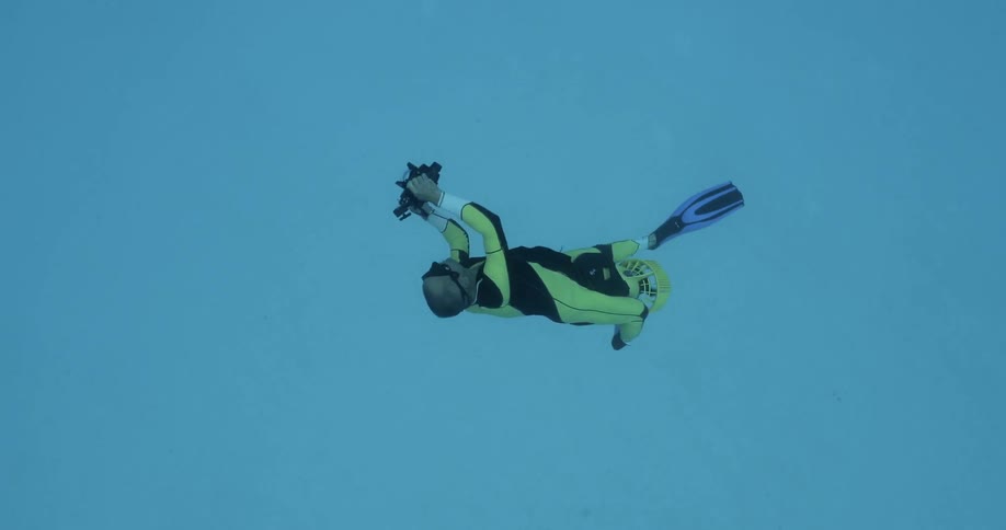 A diver is filming dolphins as they race and play around him underwater