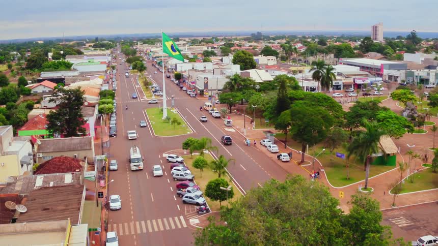Vehicles drive down a boulevard with a flag waving in the middle
