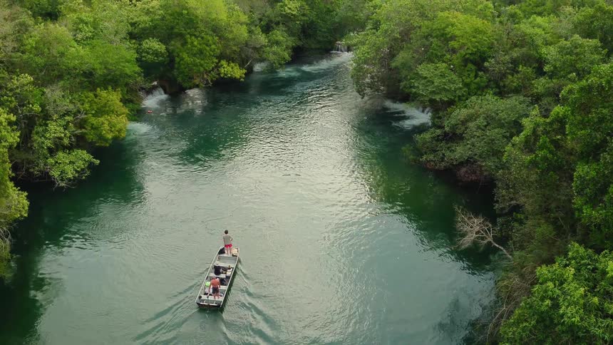Boat floats down a tree lined river