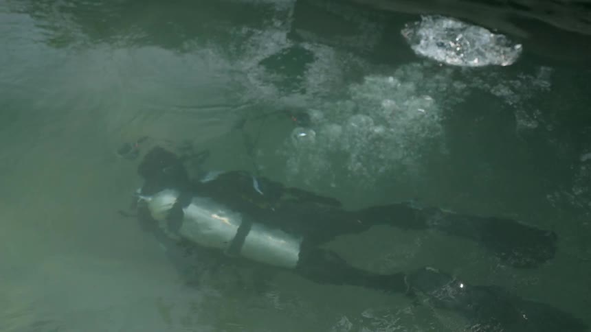 Deep sea diver creates bubbles as he swims under the water