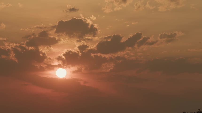 Clouds float in front of the setting sun