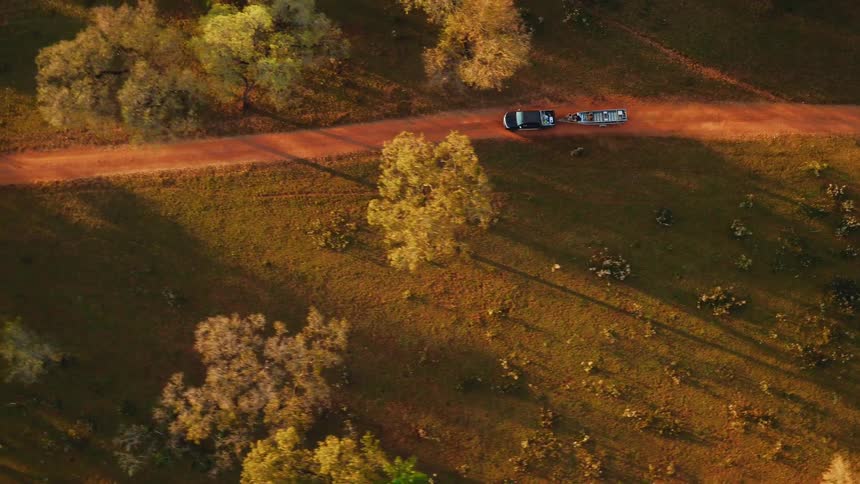 Vehicle pulling a boat on a narrow dirt road as seen from directly above