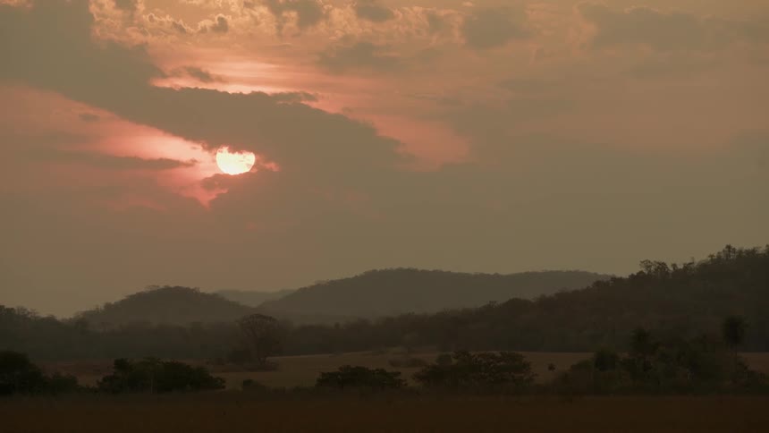The sun sets over a rural landscape