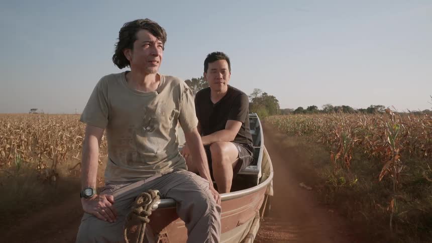 Men ride in a boat being pulled by a truck